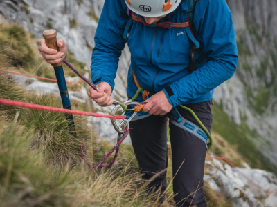 How to tie and test a short safety belay for steep grassy cliff exits using a walking pole and looped webbing